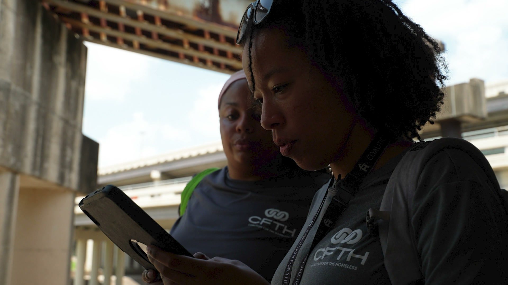 Two Coalition for the Homeless outreach workers look at a phone together