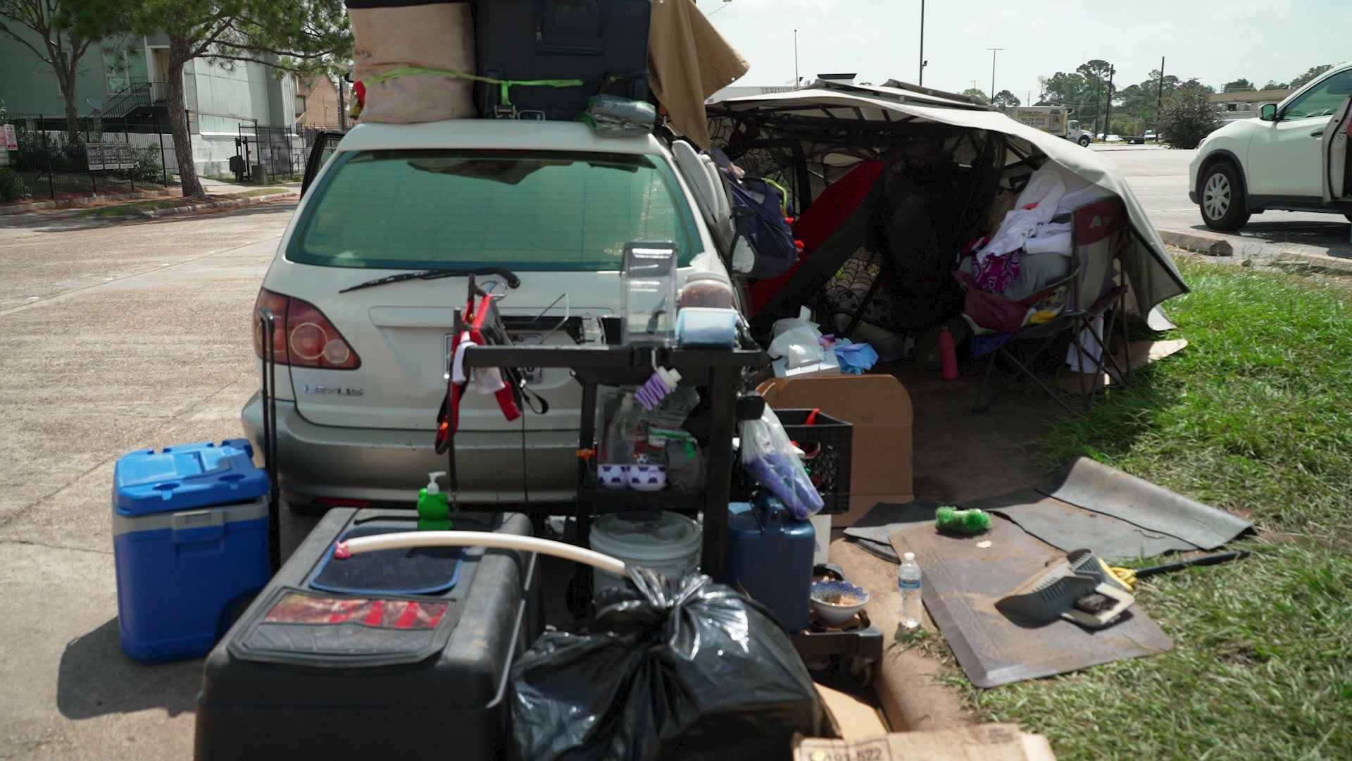 The Lexus with its hatch open and belongings spread on the grass and pavement around it