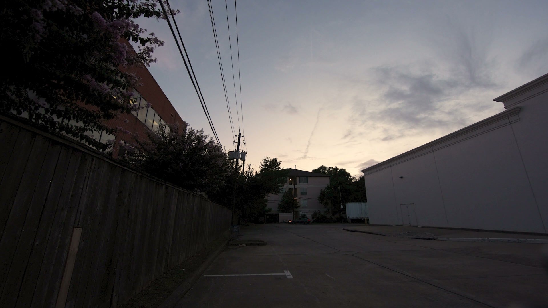An empty parking area behind buildings at dusk
